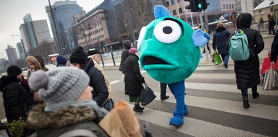 Person dressed up in a fish out fit on a busy street