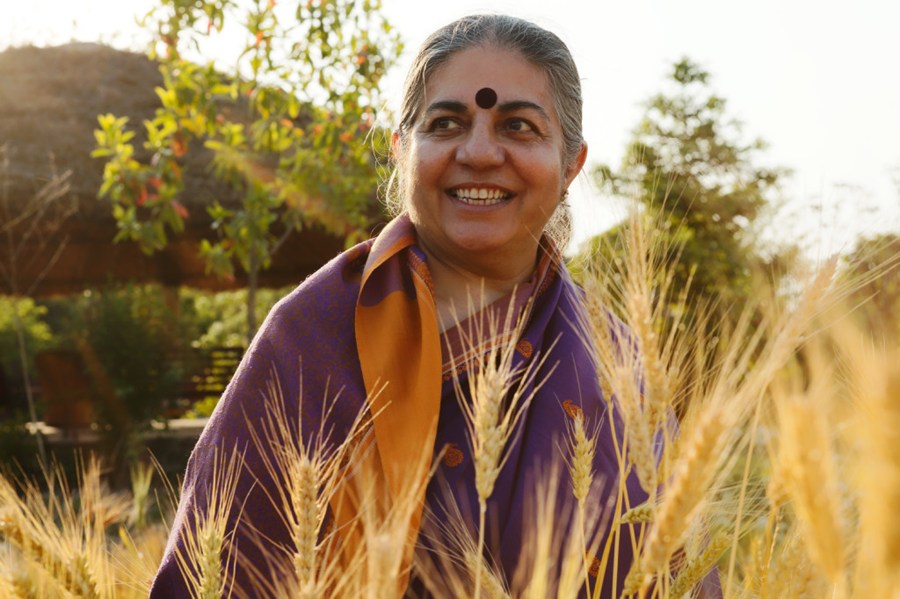 Vandana Shiva in a field smiling looking off camera